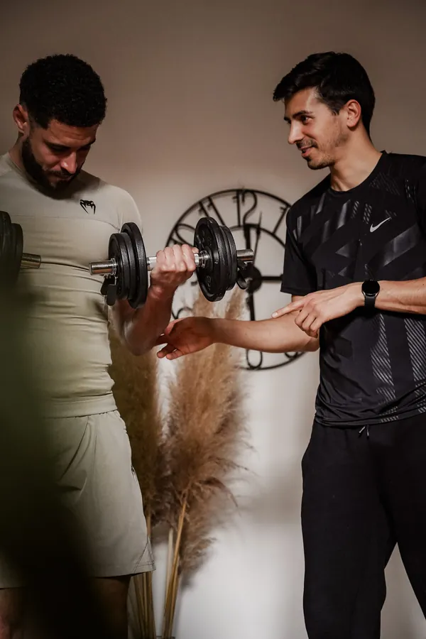 Guillaume, coach sportif, corrige la position du coude de son client pendant un exercice à domicile