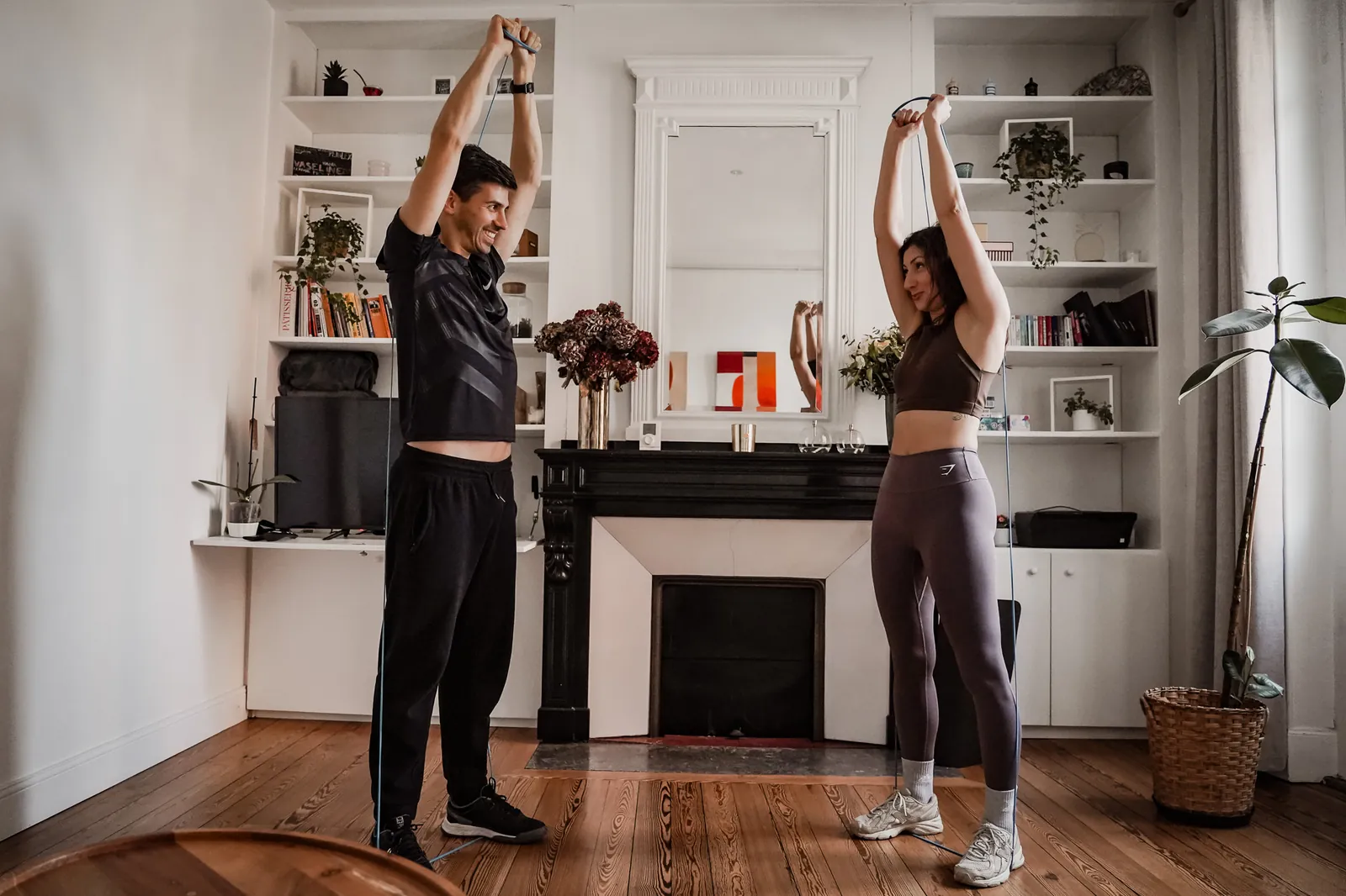 Séance de coach sportif à domicile à Toulouse : étirement des épaules avec un élastique dans le salon