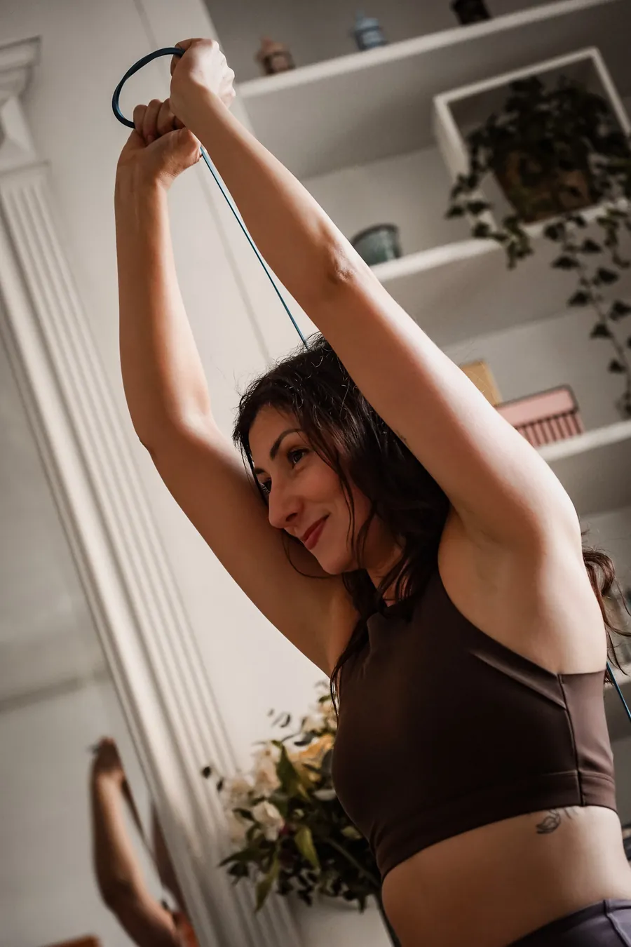 Cliente étirant le haut du dos avec un élastique, bras au-dessus de la tête, pendant une séance à domicile