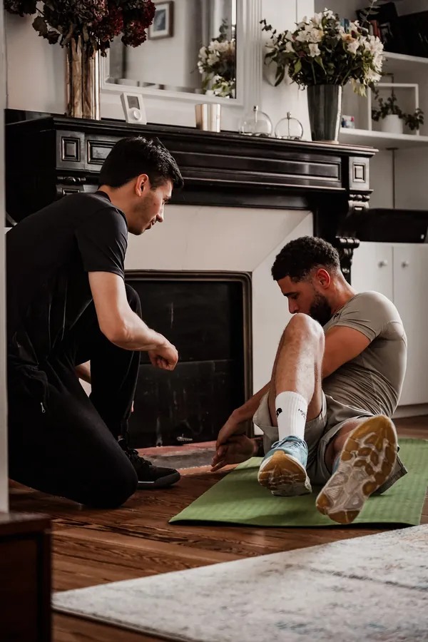 Coach sportif à domicile guidant un exercice de renforcement des jambes au sol, sans impact pour les genoux