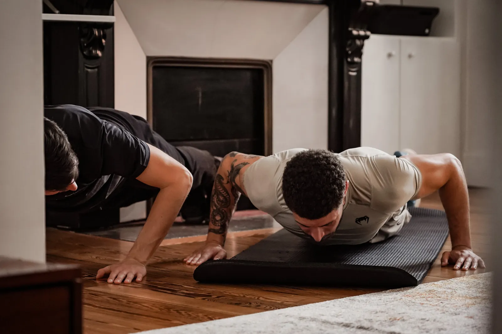 Coach sportif à domicile à Toulouse faisant des pompes à côté de son client, dans le salon, pendant une séance pour perdre du poids