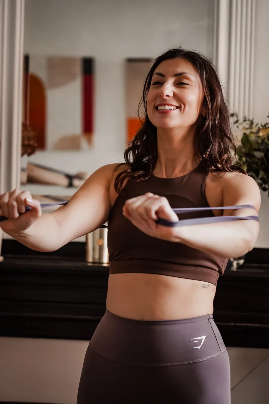 Cliente souriante renforçant le haut du corps avec un élastique dans son salon